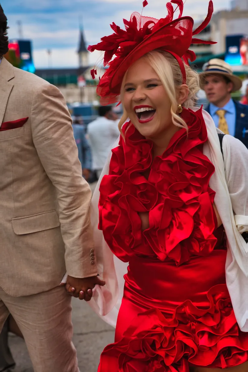 A Derby guest in red laughing at Churchill Downs