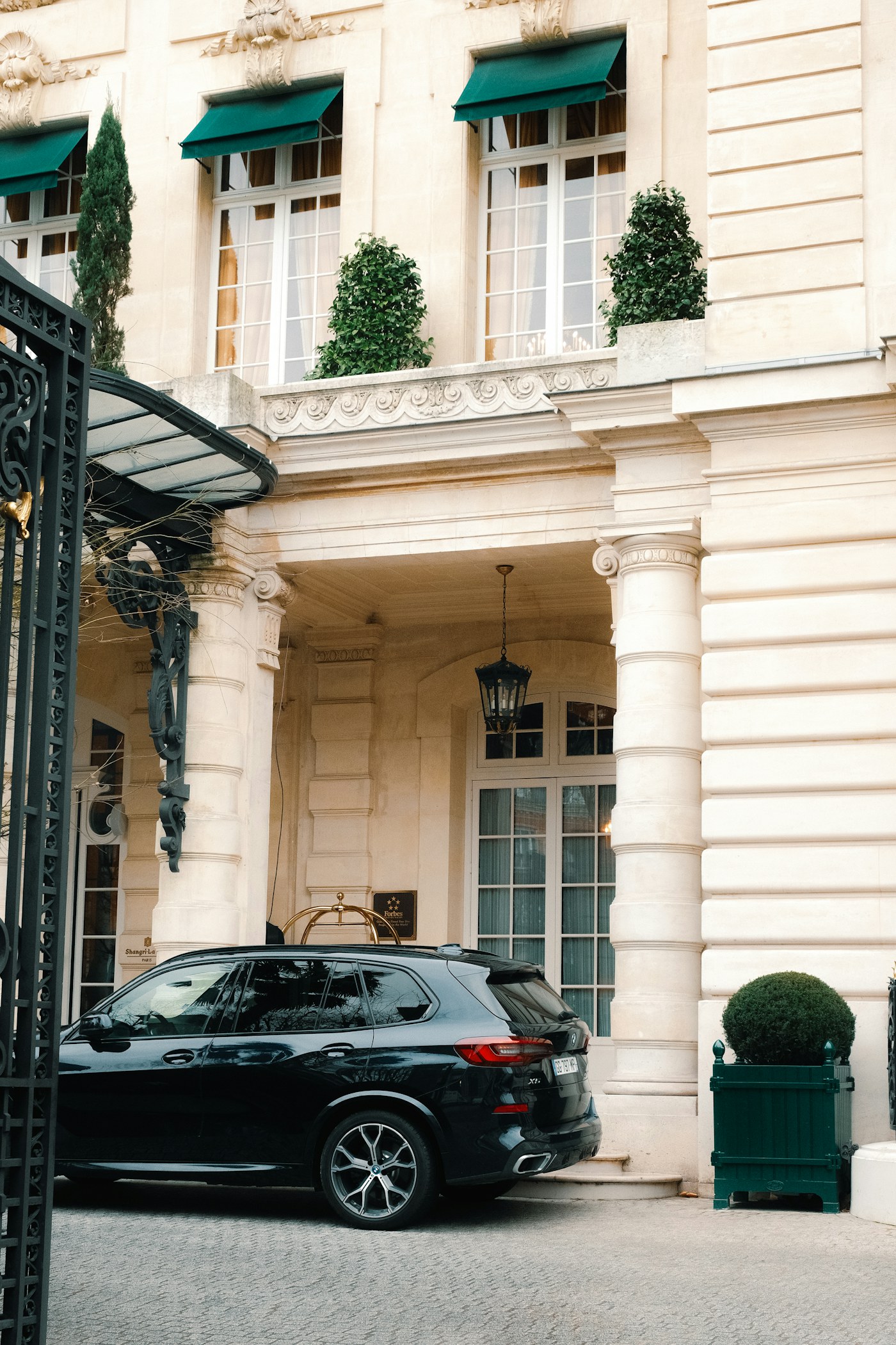 A black luxury SUV waiting at the entrance of an elegant hotel